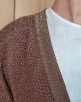 Ruana tejida en algodón con destellos de lurex, de corte amplio y diseño abierto, con textura en punto relieve.