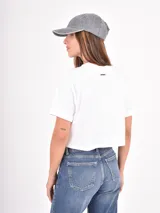 Remera blanca de corte crop, con cuello redondo, mangas cortas y estampa frontal con texto en tipografía cursiva.