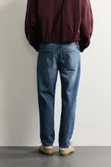 Jeans de corte slim cropped confeccionados en denim de algodón rígido con efecto lavado. Presentan tiro medio, cierre frontal con cremallera y botón, y diseño clásico de cinco bolsillos.