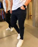 Jean skinny negro de corte ajustado, con elasticidad, bolsillos clásicos y cierre frontal con botón y cremallera.