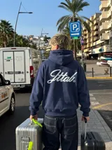 Hoodie azul marino con capucha y bolsillo frontal tipo canguro. Presenta un estampado gráfico en la espalda con la palabra 'Jttab' en tipografía cursiva blanca.