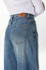 Pantalón jean de tiro alto y corte wide leg en tono azul medio, con diseño relajado.