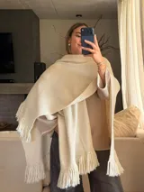 Ruana tejida a mano en lana merino, con diseño de punto arroz y terminación de flecos en los bordes.