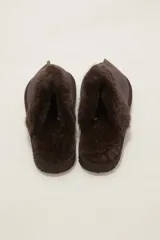 Pantuflas cerradas color marrón con ribetes de piel sintética en la abertura y suela plana.