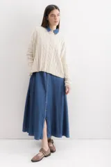 Sweater de punto con diseño de trenzas verticales, cuello redondo y corte holgado. Presenta una etiqueta de cuero sintético con el logo de la marca en la parte inferior.