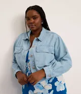 Campera de jean celeste de algodón con cuello inglés, abotonada, de manga larga ajustada con elástico en la cintura.