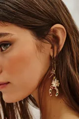 Aro colgante dorado con dije de corazón rojo, trébol de cuatro hojas con pedrería y herradura con gemas de colores.