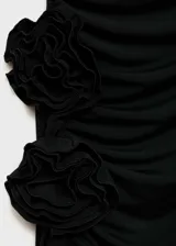 Vestido largo negro de diseño entallado, con escote palabra de honor y sin mangas. Presenta un detalle de flores 3D en la cintura y una apertura lateral en el bajo.