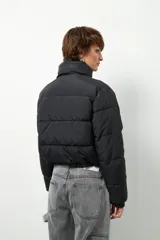 Campera puffer corta color beige de nylon, con cuello alto, cierre frontal y bolsillos laterales con cierre.