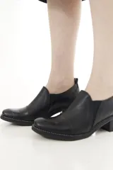 Zapatos de cuero negro con textura de cocodrilo en la puntera y el talón, de corte bajo, con elásticos laterales y taco cuadrado.