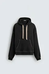 Sudadera tipo hoodie de corte relajado, color negro, con interior perchado. Presenta capucha ajustable con cordones en color crudo, bolsillo frontal tipo canguro y costuras a contraste en color blanco. Posee puños y ruedo en rib.