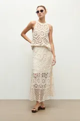Falda midi beige de tejido crochet con diseño de motivos geométricos perforados.