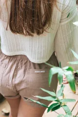 Short color beige con cintura elástica ajustable con cordón, bolsillos laterales y logo estampado en la pierna izquierda.