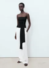 Pantalón de traje tiro medio, color blanco, de diseño recto y largo, con cierre delantero de botón, gancho y cremallera, detalle de pinzas y dos bolsillos laterales.