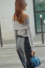 Jersey de punto liso color negro, con escote recto tipo off-shoulder con vuelta y manga larga.