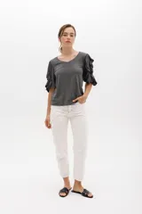 Remera color beige con mangas cortas y volados con borde naranja.