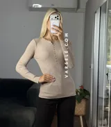 Remera de punto acanalado con escote redondo y cierre frontal parcial con botones. Presenta mangas largas y un ajuste entallado al cuerpo.