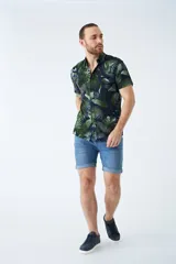 Camisa de manga corta con estampado botánico de hojas en tonos azul y blanco. Presenta cuello clásico, cierre frontal abotonado y corte slim.