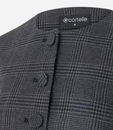 Blazer de sastrería color gris con estampado de cuadros, cuello redondo y cierre frontal con botones forrados. Presenta mangas largas con volumen tipo baloné y bolsillos frontales con solapa.