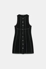 Vestido mini negro con cuello redondo y diseño sin mangas, con pespuntes en contraste y botones decorativos frontales.