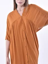 Vestido midi de corte holgado y diseño oversize, color naranja, con cuello en V, cierre frontal con botones y mangas cortas amplias.