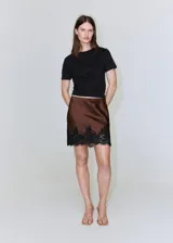 Minifalda marrón satinada con estampado de lunares negros y detalle de puntilla de encaje negro en el ruedo.