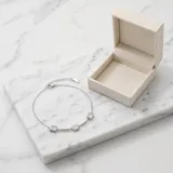 Pulsera de cadena fina de acero con tres dijes cuadrados engastados con circonias blancas.