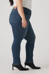 Pantalón de jean azul oscuro, tiro medio, corte ajustado y largo hasta el tobillo.