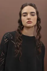 Sweater de punto color negro, de corte holgado y manga larga, con detalle de bordado calado en los hombros y a lo largo de las mangas.