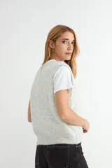 Chaleco de punto color crema con escote en V, sin mangas y diseño decorado con pequeñas perlas aplicadas en toda la superficie.