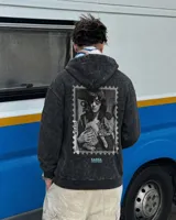 Canguro con capucha de algodón y poliéster, color negro con efecto acid wash, corte regular fit y estampa en la espalda con diseño en blanco y negro de una persona con un gato dentro de un sello postal, acompañada de texto en celeste.