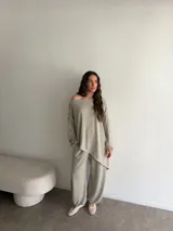 Conjunto gris melange compuesto por un buzo de cuello bote amplio y corte asimétrico con bolsillos, y un pantalón largo de corte recto y holgado.