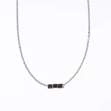 Collar plateado con cadena fina y tres dijes cuadrados pequeños.