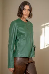 Campera de cuero con cierre frontal, cuello redondo y detalles de tachas metálicas en el escote.