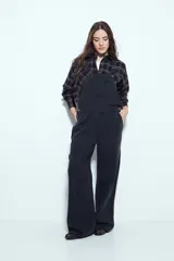 Enterito de denim negro con calce relajado y silueta amplia, inspirado en la estética workwear. Presenta tiradores regulables, pechera con bolsillo frontal y bolsillos laterales funcionales.