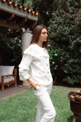 Campera de jean blanca con volados en el frente y las mangas, confeccionada en algodón y lino.