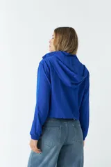 Campera deportiva corta color negro, con capucha ajustable y bolsillos frontales.