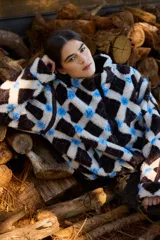 Campera de corderito con diseño de rombos en tonos marrón, crema y azul. Presenta cuello alto, cierre frontal completo y ajuste elástico en la cintura.