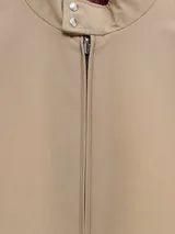 Campera cazadora reversible Moncler, con diseño acolchado en color bordó de un lado y color beige del otro. Presenta cuello tipo bomber con franjas, cierre frontal con cremallera y puños elásticos a rayas.