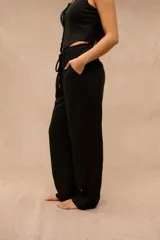 Pantalón largo negro de corte holgado, con cintura elástica ajustable mediante cordón y bolsillos laterales.