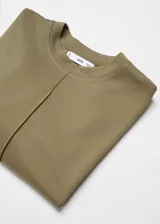 Buzo de cuello redondo y manga larga, confeccionado en tejido de piqué con costuras decorativas verticales en el frente. Presenta un diseño recto y holgado.