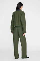 Chaqueta Yuma de inspiración utilitaria, color verde militar, confeccionada en algodón estructurado con acabado suave y desgastado. Presenta una silueta relajada, bolsillos de parche frontales y cierre de botonadura central con botones en tono gris plomo.