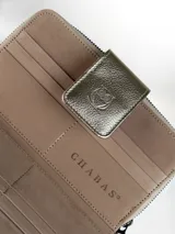 Billetera grande de cuero en color natural, con solapa externa en cuero metalizado dorado que presenta un logo grabado de un búho. El interior cuenta con múltiples ranuras para tarjetas y el nombre de la marca grabado.