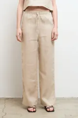 Pantalón color arena, de corte recto y tiro alto, confeccionado en lino.