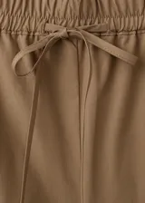 Pantalón marrón de corte recto, con cintura ajustable elastizada y cordón, y detalle de franja lateral bordada con diseño calado.