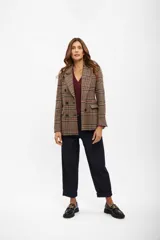 Blazer de corte sastrero con diseño de cuadros tipo príncipe de Gales en tonos marrones, azul y rojo. Presenta cierre frontal cruzado con doble botonadura, solapas clásicas y bolsillos laterales con solapa.
