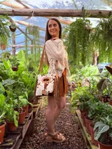 Bandolera de cuero con estampado animal print de vaca en tonos marrón y blanco, con flecos de cuero marrón en los laterales. Tiene correa larga de cuero marrón regulable y asa de mano con forma ovalada.