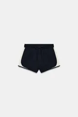 Short de tiro medio confeccionado en algodón, con cintura elástica ajustable mediante cordón y diseño combinado con laterales en color contrastante.