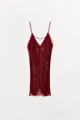 Vestido corto color rojo oscuro (vino) con escote en V pronunciado y tirantes finos. Presenta un diseño con flecos o tiras superpuestas que caen verticalmente y terminación en encaje festoneado en el ruedo y el escote.