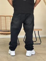 Pantalón tipo cargo de denim color negro con efecto lavado. Presenta corte holgado, bolsillos laterales con solapa y costuras reforzadas en las rodillas.